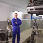 smiling-mechanic-standing-car